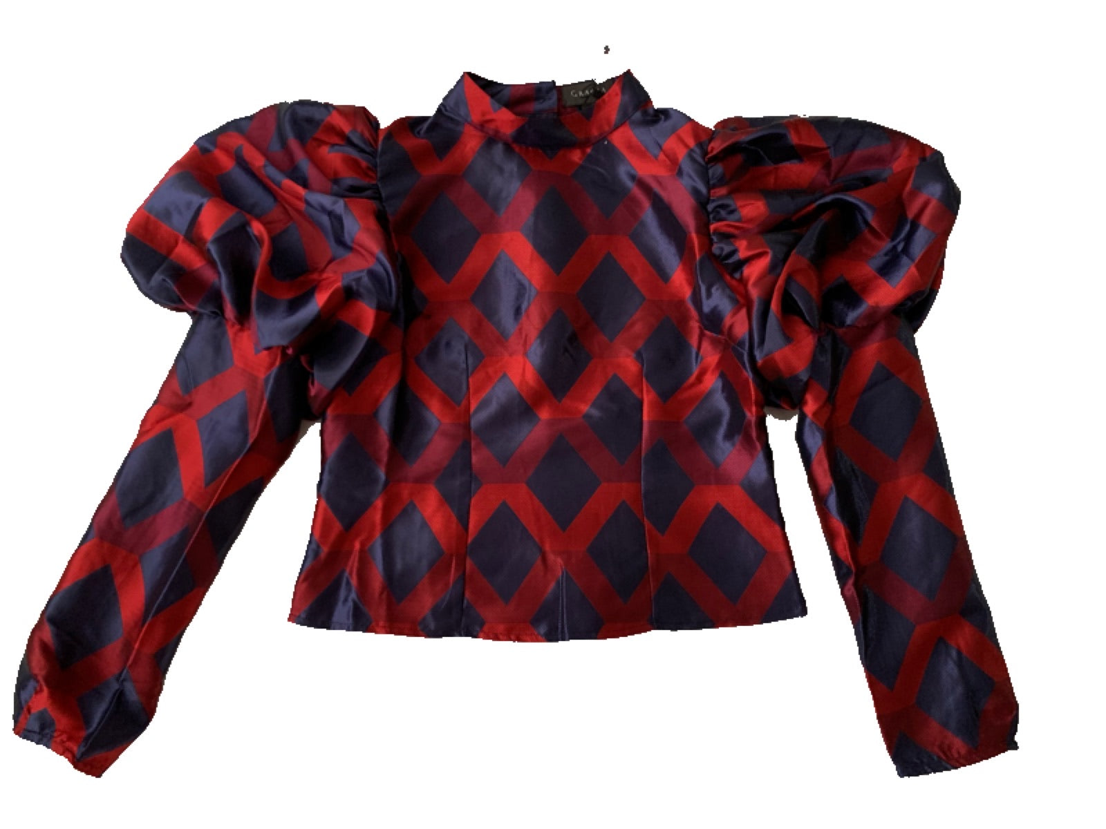 Blouse in three colors, purple, red and dark blue. Goes up to the neck and puff sleeves at the shoulder. It is tied in the back with buttons.